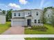 Beautiful two-story home featuring gray siding, a brick driveway and manicured lawn at 1169 Happy Forest Loop, Deland, FL 32720