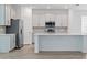 Well-lit kitchen with stainless steel appliances, an island with bar seating and white cabinets at 1169 Happy Forest Loop, Deland, FL 32720