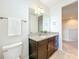 Bathroom vanity with dark wood cabinets, granite countertop, mirror, and a view into the hallway at 14014 Millington St, Orlando, FL 32832