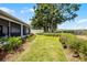 Landscaped backyard featuring a well-maintained lawn, garden beds, and a screened patio at 14723 Peppermill Trl, Clermont, FL 34711