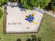 Aerial view of a fenced playground with colorful play equipment, benches, and a sandy surface, perfect for community fun at 14723 Peppermill Trl, Clermont, FL 34711