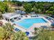 Overhead view of a community pool, featuring lounge chairs, umbrellas, and palm trees at 14723 Peppermill Trl, Clermont, FL 34711