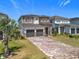 Beautiful two-story home with a brick driveway, gray garage doors and a well-manicured lawn at 15727 Vetta Dr, Montverde, FL 34756