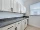 Functional laundry room showcasing granite countertops, white cabinets, and modern black hardware at 15727 Vetta Dr, Montverde, FL 34756