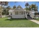 Inviting home exterior featuring a metal roof, covered porch, manicured lawn, and tasteful landscaping at 246 N Oak Ave, Orange City, FL 32763