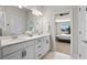 Bright bathroom with a double sink vanity featuring modern fixtures and a view of the primary bedroom through an open doorway at 327 Island Sound Ct, Longwood, FL 32779