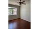 An empty bedroom featuring hardwood floors, a ceiling fan, and a window looking out to the trees at 3344 Corona Village Way # 205, Orlando, FL 32835