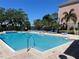Community pool with blue lounge chairs, palm trees, and blue skies at 3344 Corona Village Way # 205, Orlando, FL 32835