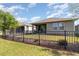 Spacious backyard with well-maintained lawn, black metal fence and covered patio with a grill at 3443 Sagebrush St, Harmony, FL 34773
