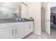 Bathroom vanity with double sinks, white cabinetry, and a view into the shower and walk-in closet at 3443 Sagebrush St, Harmony, FL 34773