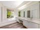 Bright bathroom with double sinks, large mirror, and soaking tub beneath a window at 3831 River Hollow Ct, Oviedo, FL 32765
