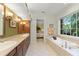 Bright bathroom features a soaking tub with jets, double vanity, and a view overlooking nature at 4000 Rouse Rd, Orlando, FL 32817
