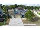 Aerial view of a two-story home with blue exterior, brown shutters, three-car garage, and solar panels at 4058 Brookshire Cir, Eustis, FL 32736