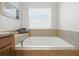 Bathroom soaking tub with tile surround near a window, providing a relaxing ambiance at 5838 Cypress Hill Rd, Winter Garden, FL 34787