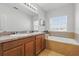 Bathroom with double sinks, granite countertops, and a large soaking tub under a window at 5838 Cypress Hill Rd, Winter Garden, FL 34787