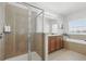Bright bathroom featuring a walk-in shower with a glass door and a soaking tub near a window at 5838 Cypress Hill Rd, Winter Garden, FL 34787