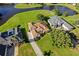 An aerial view showcasing a property with a well-manicured lawn, beautiful landscaping, and a nearby lake at 7351 Spring Mountain Ln, Yalaha, FL 34797
