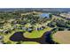 Scenic aerial view of a lush residential community featuring homes surrounding a pond and verdant green spaces at 7351 Spring Mountain Ln, Yalaha, FL 34797