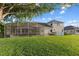 A spacious backyard features a screened in pool, lush green lawn, and mature trees at 7351 Spring Mountain Ln, Yalaha, FL 34797