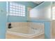 Bathroom featuring a luxurious soaking tub with tile surround and a glass block window at 7351 Spring Mountain Ln, Yalaha, FL 34797