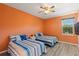 Bright bedroom featuring twin beds with blue bedding, ceiling fan, and a window with a view at 7351 Spring Mountain Ln, Yalaha, FL 34797