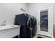 Modern laundry room features a dark blue washer and dryer set next to a utility sink and a door to the outside at 7351 Spring Mountain Ln, Yalaha, FL 34797