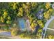 Aerial shot of a tennis court surrounded by trees, showcasing a nearby residence at 7351 Spring Mountain Ln, Yalaha, FL 34797