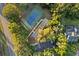 Overhead view of a community tennis court with parking, surrounded by mature trees and landscaping at 7351 Spring Mountain Ln, Yalaha, FL 34797