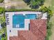 An aerial view of the home's backyard featuring a pool, hot tub and sun loungers next to the home with a terracotta roof at 971 Golden Bear Dr, Reunion, FL 34747