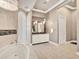 Luxurious bathroom with marble tiling, crystal chandelier, soaking tub, and double vanity with large mirrors at 971 Golden Bear Dr, Reunion, FL 34747