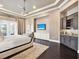 Bright bedroom features a plush rug, tray ceilings, and wet bar with sink and drink refrigerator at 971 Golden Bear Dr, Reunion, FL 34747