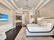 Bright bedroom features a plush rug, tray ceilings, wet bar, and luxurious bed with a padded headboard at 971 Golden Bear Dr, Reunion, FL 34747