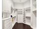 Spacious walk-in closet featuring custom shelving, drawers, and ample storage space with dark hardwood flooring at 971 Golden Bear Dr, Reunion, FL 34747