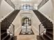 Grand foyer with a double staircase, wrought iron railings, and elegant tile flooring at 971 Golden Bear Dr, Reunion, FL 34747