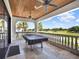 An outdoor patio with ceiling fans, a pool table, and a stone balustrade overlooking a beautiful golf course at 971 Golden Bear Dr, Reunion, FL 34747