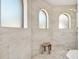Bright bathroom shower with neutral tile, a wooden seat, and arched windows providing natural light and ventilation at 971 Golden Bear Dr, Reunion, FL 34747