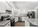 Well-lit kitchen features stainless steel appliances, gray countertops and plentiful white cabinetry at 992 Woodrose Ct, Altamonte Springs, FL 32714