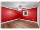 Bedroom features hardwood floors, a ceiling fan, and a bright red accent wall at 1105 Lake Nettie Dr, Eustis, FL 32726