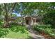 Charming home with mature trees, blooming flowers, and a covered entryway at 1105 Lake Nettie Dr, Eustis, FL 32726