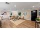 Bright living room featuring wood floors, modern furniture, and a decorative round mirror at 1105 Lake Nettie Dr, Eustis, FL 32726