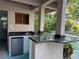 Outdoor kitchen with granite countertop, sink, wood shutters, and mini-refrigerator offers poolside convenience at 1105 Lake Nettie Dr, Eustis, FL 32726