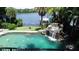 Inviting pool area featuring a soothing rock waterfall and lush tropical landscaping, perfect for relaxation and entertainment at 1105 Lake Nettie Dr, Eustis, FL 32726