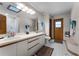Bathroom featuring dual sinks, white vanity, wood trim, and skylight for natural light at 1689 Saboff Way, Chuluota, FL 32766