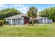 Charming single-story home with a well-manicured lawn, palm tree, and inviting red front door at 1689 Saboff Way, Chuluota, FL 32766