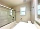 Bathroom features a glass-enclosed shower, white vanity, and plenty of natural light at 2648 Needlepoint St, Kissimmee, FL 34741