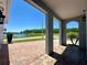 Covered front porch with brick flooring provides a view of a serene lake surrounded by lush trees at 2648 Needlepoint St, Kissimmee, FL 34741