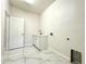 A clean laundry room boasts a white sink and cabinet combo, sleek tile flooring, and ample natural light at 2648 Needlepoint St, Kissimmee, FL 34741