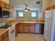 Well-lit kitchen with wood cabinets, tile flooring and modern appliances open to the dining area at 266 Paradise Woods Ct, Davenport, FL 33896