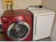 Convenient laundry area features a red Whirlpool washer and a white Samsung dryer for easy garment care at 266 Paradise Woods Ct, Davenport, FL 33896