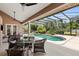 Outdoor lanai with a table and chairs, a screened-in pool and lush landscaping at 2825 Lakeshore Dr, Mount Dora, FL 32757